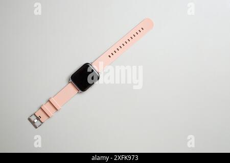 Orologio intelligente con bracciale in gomma rosa su sfondo grigio, piatto Foto Stock