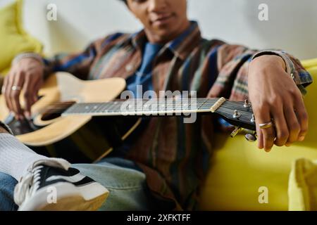 Serenate giovanili con chitarra acustica su un comodo divano giallo. Foto Stock