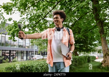 Un giovane afroamericano sorride mentre si fa un selfie in un parco. Foto Stock