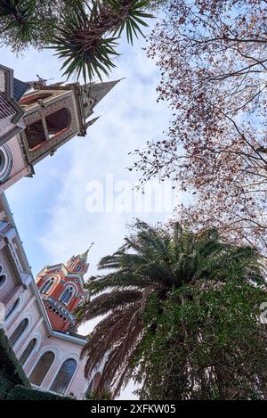 Vista dal basso della chiesa romanica e dell'abbazia di Buenos Aires. Foto scattata dal cortile con palme e querce. C'è una guglia alta, un cr latino Foto Stock
