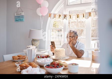Casa, triste e compleanno per anziano, cellulare e solitario per festeggiare, inviare messaggi e comunicare. Depressione, pensiero e persona anziana con Foto Stock