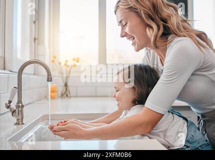 Madre, ragazza e lavare le mani in cucina per l'igiene, la pulizia e l'acqua per proteggersi dai germi. Mamma, figlia e liquido per la cura della pelle o. Foto Stock