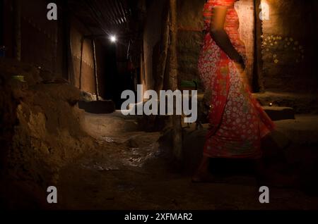 Woman walking with domestic cat following in alley. Aarey Milk Colony in unofficial buffer zone of Sanjay Gandhi National Park, Mumbai, India. January Stock Photo