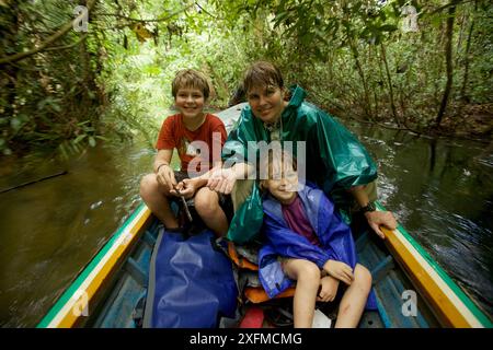 La ricercatrice di orangutan Cheryl Knott e i bambini viaggiano in barca lungo il fiume dalla stazione di ricerca di Cabang Panti, al Parco Nazionale di Gunung Palung, Borneo. Agosto 2010 rilasciato il modello. Foto Stock