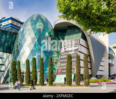 Baku, Azerbaigian - 10 maggio 2024: Poche persone camminano vicino al design moderno del centro commerciale Park Bulvar, in una giornata primaverile, con cieli azzurri Foto Stock