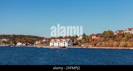 Vista del paesaggio costiero norvegese con fienile di legno bianco e case sulla costa rocciosa. Kristiansund, Norvegia Foto Stock