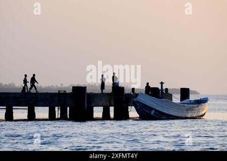 Persone al molo nel villaggio di pescatori di Cacheu, al tramonto, fiume Cacheu, Guinea Bissau, febbraio 2015. Foto Stock