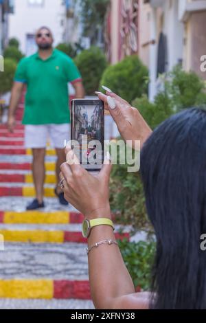 Questa immagine mostra una donna che scatta una fotografia di un uomo nella pittoresca città di Calpe, in Spagna. Foto Stock