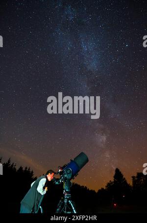 Uomo che guarda attraverso un telescopio al cielo notturno, Eifel Dark Sky Park, Eifel National Park, Germania, settembre 2016. Foto Stock