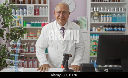 Un anziano uomo caucasico dai capelli grigi in una farmacia in piedi dietro il bancone, circondato da vari prodotti e una pianta, sorridendo calorosamente in un pozzo Foto Stock