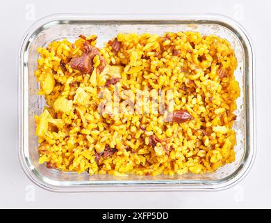 Un piatto fumante di paella spagnola fatta in casa con riso, pesce e pollo in un piatto da forno in vetro trasparente. Foto Stock