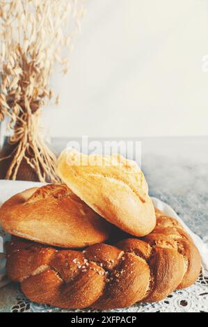 Diversi tipi di pane - kalacha, hala - pane intrecciato con sale grossolano. Pane sul tavolo con bollitore e caraffa, preparato per il consumo. Assortimento di Foto Stock