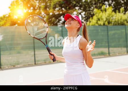 Giovane tennista eccitata che celebra la vittoria sulla carta, la coppa di tennis, la vittoria nel tennis, il grande concetto di tennis Foto Stock