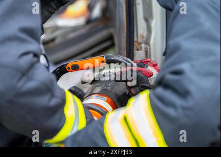 Vigili del fuoco che utilizzano attrezzi idraulici durante un addestramento per operazioni di soccorso. I soccorritori sbloccano il passeggero in auto dopo un incidente. Fotografia di alta qualità Foto Stock