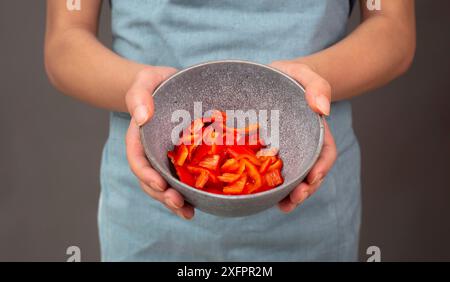 Peperoni rossi a fette in una ciotola, preparare cibo sano con verdure di paprika, tenendo in mano la nutrizione biologica fresca Foto Stock