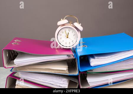 Sveglia in piedi su una pila di cartelle di file, esaurimento, stress e sovraccarico, pressione sul lavoro, scadenza Foto Stock