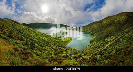 Un lago limpido circondato da verdi colline e montagne sotto un cielo blu con nuvole in una giornata di sole, il lago cratere Lagoa do Fogo, Caldeiras, Sao Miguel Foto Stock