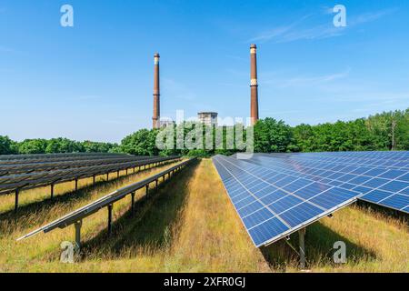 Moduli solari di un parco solare di fronte alla centrale elettrica a lignite di Plessa dismessa con due camini e torri di raffreddamento, Plessa, Lusazia Foto Stock