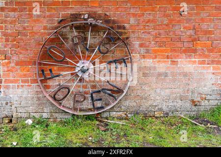 Ruota di ferro con "Forge Open" su un muro di un ex fabbro a Chiddingfold, un villaggio nel Surrey, nel sud-est dell'Inghilterra Foto Stock