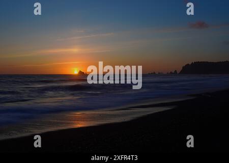 Il sole tramonta dietro una pila di mare a Rialto Beach nell'Olympic National Park di Washington. Foto Stock