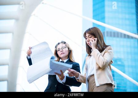 Imprenditrice felice donne d'affari asiatiche che usano lo smartphone che trattano per l'impresa di startup. Due partner ricevono buone notizie dal lavoro di squadra su smartphone Foto Stock