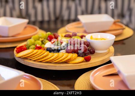 Serve frutta assortita e cracker su un piatto di legno per riunioni a casa Foto Stock