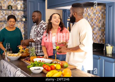 Preparare il cibo e godersi la conversazione, incontrare amici diversi nella cucina moderna Foto Stock