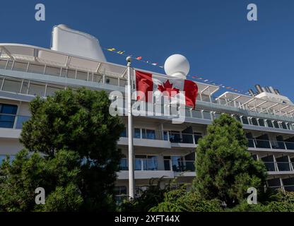 Vancouver CAN, Kanada / Canada, Urlaubseindruecke und Sehenswuerdigkeiten, Vancouver, Downtown, 04.07.2024. Die Silver Nova - ein neu gebautes Kreuzfahrtschiff - liegt im Vancouver Harbour am Canada Place an der Waterfront vor Anker. Davor eine kanadische Fahne mit dem Ahornblatt. CAN, Kanada / Canada, Urlaubseindruecke und Sehenswuerdigkeiten, Vancouver, Downtown, 04.07.2024. *** Vancouver CAN, Canada Canada, impressioni di vacanza e luoghi di interesse, Vancouver, Downtown, 04 07 2024 la Silver Nova, una nave da crociera di nuova costruzione, è ancorata nel Porto di Vancouver presso Canada Place sul lungomare Foto Stock