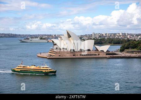 Sydney Opera House con traghetto MV Freshwater di passaggio, base navale di Garden Island con HMAS Canberra nel porto, Sydney, NSW, Australia Foto Stock