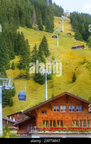 Kandersteg, stazione della funivia svizzera per Oeschinensee, cabine blu e case di villaggio in estate Foto Stock