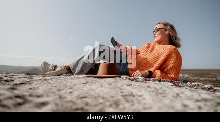 Donna che si rilassa sulla cima di una montagna con vista Foto Stock