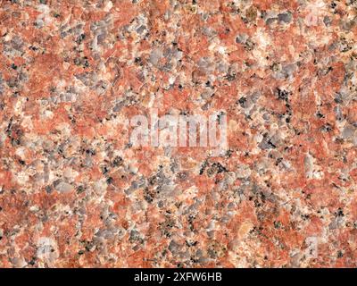 Foto di granito rossastro, adatto per l'uso come texture o sfondo. Il dettaglio in pietra naturale aggiunge un Foto Stock
