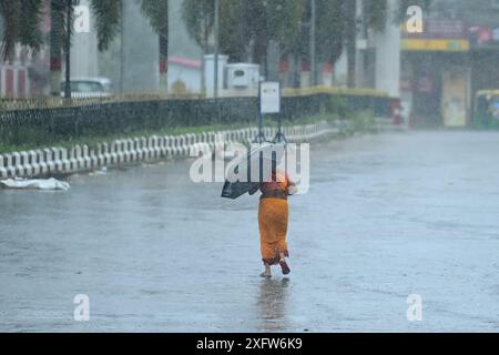 Una donna che attraversa una strada deserta in forte pioggia durante il Cyclone Remal ad Agartala. Tripura, India. Foto Stock