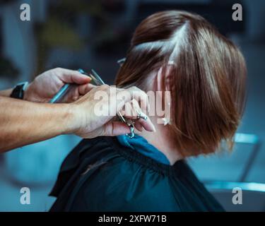 Le mani del parrucchiere mostrano di tagliare i capelli della donna. Parrucchiere che taglia i capelli della donna. Donna con taglio a filo. Salone di parrucchiere. Primo piano del taglio dei capelli femminile. Pro Foto Stock