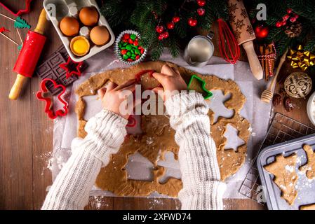 Preparazione dei biscotti natalizi di famiglia. La madre e la figlia hanno una vista dall'alto su un intimo sfondo di legno, mentre preparano biscotti al pan di zenzero con biscotti tagliati Foto Stock