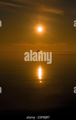 Sole basso sul mare Novaya Zemlya, Artico russo, con barca in lontananza 2017 luglio, luglio Foto Stock