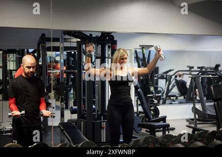 Donna determinata che fa esercizio con il manubrio in palestra Foto Stock