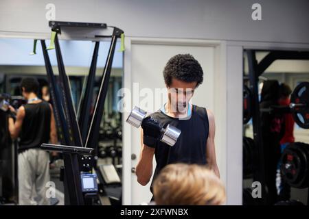 Giovane uomo che esercitano con il manubrio in palestra Foto Stock