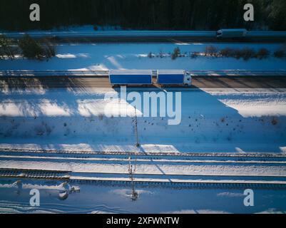 Vista del camion su un'autostrada vicino ai binari della ferrovia in mezzo alla neve Foto Stock