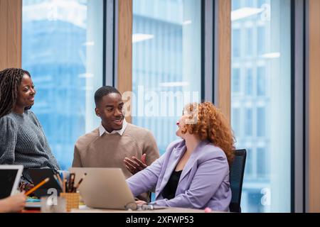 Sorridere i colleghi aziendali che parlano mentre lavorano in ufficio Foto Stock