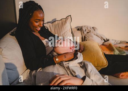 Uomo sorridente sdraiato in grembo alla ragazza a casa Foto Stock
