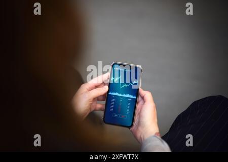 Immagine ritagliata di una donna d'affari che analizza il grafico sul telefono cellulare Foto Stock