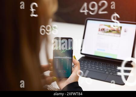 Immagine generata digitalmente di una donna d'affari che analizza il grafico al telefono mentre lavora in ufficio Foto Stock