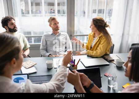 Donna d'affari che condivide idee con i colleghi in ufficio Foto Stock