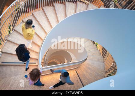 Vista ad angolo elevato dei colleghi che si spostano su una scala a chiocciola in ufficio Foto Stock