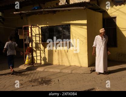 Luce solare serale nella città vecchia di Mombasa con un vecchio che indossa abiti tradizionali Foto Stock