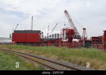 un sito industriale con grandi gru e parti di gru a torre per il sollevamento e il trasporto di oggetti pesanti Foto Stock