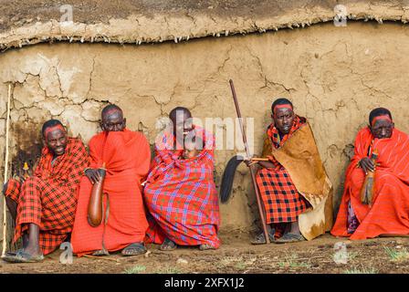 Anziani del villaggio Maasai, uno con il bambino. Con gole per bere di fronte alla capanna, il villaggio di Maasai, Kenya. Settembre 2006. Foto Stock