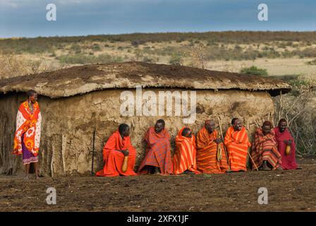 Anziani del villaggio Maasai con gole alcoliche e donna Maasai di fronte alla capanna, villaggio Maasai, Kenya. Settembre 2006. Foto Stock