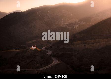 Una piccola chiesa greca illuminata dal sole mentre sorge su una collina a Olimpo, Karpathos, Grecia. Foto Stock